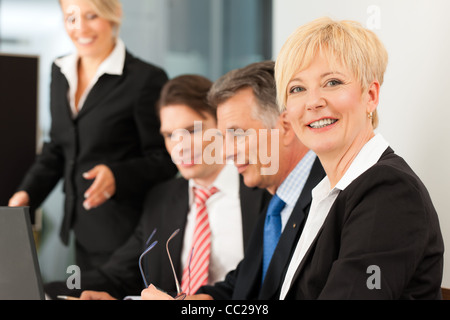 Business - sucht Team-Meeting in einem Büro mit Laptop, der Chef mit seinen Mitarbeitern, eine Frau in die Kamera Stockfoto