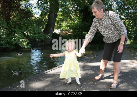 Junges Mädchen und Großmutter Blick auf Enten auf einem Fluss Burford Cotswolds Oxfordshire Stockfoto