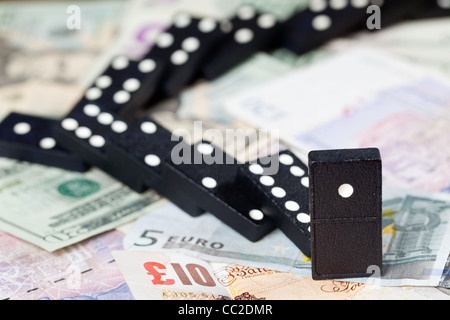 Gefallenen Dominos auf Pfund, Euro und Dollar-Banknoten, die zur Veranschaulichung Bankenkrise Stockfoto