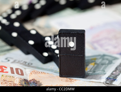 Gefallenen Dominos auf Pfund, Euro und Dollar-Banknoten, die zur Veranschaulichung Bankenkrise Stockfoto
