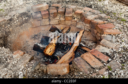 Alten, gemauerten Feuerstelle mit hölzernen Maschinenbordbüchern Schwelbrand Stockfoto