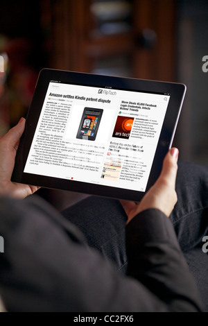 Nahaufnahme einer Frau im Wohnzimmer entspannen beim Lesen von Nachrichten von Flipboard app auf ihrem iPad 2 Stockfoto