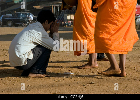 Buddhistische Mönche stehen während des Empfangs Reis von einem Mann in Ban Lung, Kambodscha auf einer unbefestigten Straße. Stockfoto