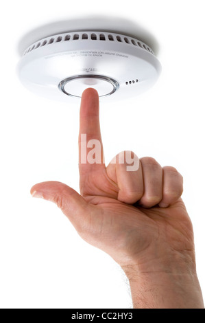 Hand mit Zeigefinger Tests eine inländische Feuer / Alarm Rauchmelder isoliert auf weißem Hintergrund Stockfoto