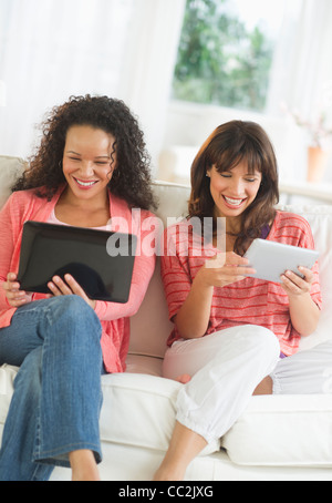 USA, New Jersey, Jersey City, zwei Frauen sitzen auf Sofa mit digitalen Tabletten Stockfoto