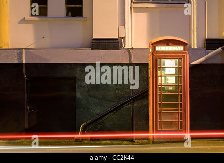Nacht Schuss von UK Phonebox mit Lichtspuren von vorbeifahrenden Autos. Stockfoto