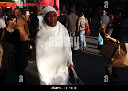 Eine afrikanische Frau in Tracht, Spaziergänge entlang der belebten Oxford Street Stockfoto