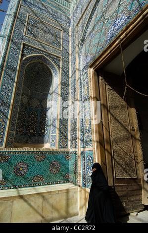 Eine Frau in einem Tschador durchläuft das atemberaubende blau gekachelten Eingangsportal, 15C (Freitag) Jameh Moschee in Yazd, Iran. Stockfoto