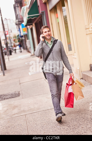 USA, New Jersey, Jersey City, Mann mit Einkaufstüten telefonieren mit Handy Stockfoto