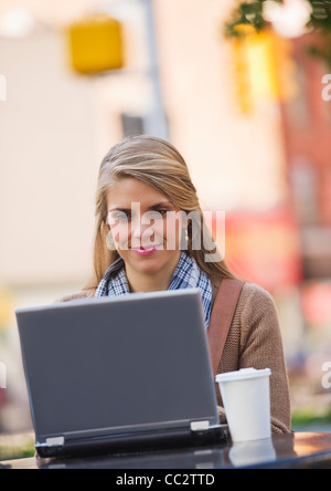 USA, New Jersey, Jersey City, junge Frau mit Laptop im Straßencafé sitzen Stockfoto