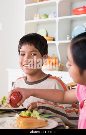 Porträt von lächelnden jungen (10-11) und Mädchen (8-9) Essen am Tisch, Los Angeles, California, USA Stockfoto