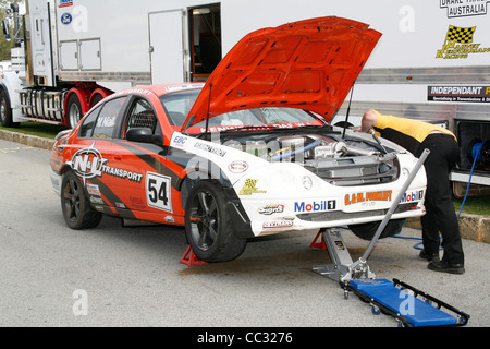 Australische Ford Falcon Rennwagen aufgebockt in die Gruben und wird von einem Mechaniker überprüft. Stockfoto