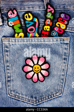 Stickerei-Eisen auf Flecken von bunten Liebe, Frieden, glücklich Worte mit einem Smiley Gesicht Blume in einem Jeans Tasche Jean Hintergrund Stockfoto