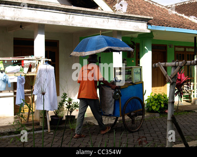 lokale Anbieter Räder seinen Eiswagen durch ein ländliches Dorf Straße Java Indonesien Stockfoto
