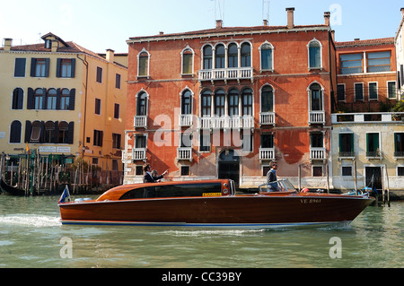 Touristen, die die historischen Sehenswürdigkeiten entlang des Canale Grande von einem traditionellen hölzernen Wassertaxi aus, Venedig, Italien, betrachten Stockfoto