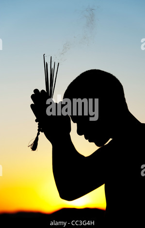 Beten mit Weihrauch indischen Mann klebt bei Sonnenuntergang. Silhouette. Indien Stockfoto