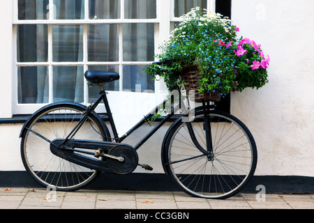 Foto von einem alten Fahrrad mit einem Korb voller Blumen und eine leere Werbetafel im Rahmen. Stockfoto