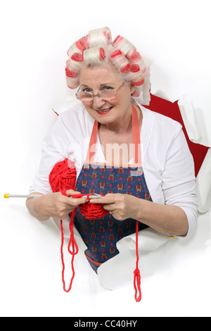 Ältere Frau mit Lockenwickler, während stricken Stockfoto