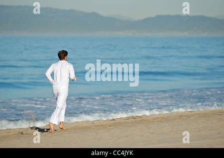 Ein Mann in laufen am Strand ganz in weiß gekleidet. Stockfoto