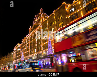 Harrods Kaufhaus in der Abenddämmerung mit Christmas lights Shopper und vorbei an Taxis und roten Busse Knightsbridge London SW1 Stockfoto