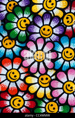 Stickerei-Eisen auf Flecken von bunten Smiley Gesicht Blumen auf schwarzem Hintergrund Stockfoto