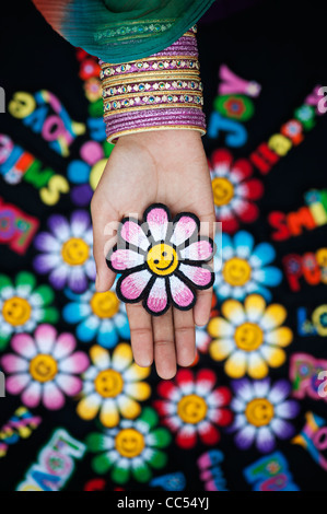 Indische Mädchen Hand mit Bügeleisen Stickerei auf Patch bunten Smiley Gesicht Blume vor anderen patches Stockfoto