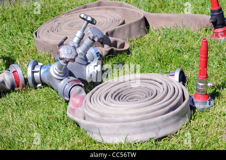 Ventile und Feuerwehrschläuche in Aktion auf dem Rasen Stockfoto