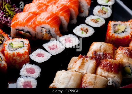 Sushi-Rollen auf einer schwarzen Platte. Stockfoto