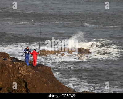 Zwei Männer Linie Angeln vom Felsen an der Nordsee-Küste in der Nähe von South Shields, Nord-Ost England UK Stockfoto