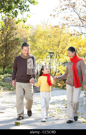 Älteres Paar mit Enkelin ein Spaziergang durch den Park im Herbst Stockfoto