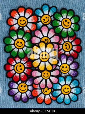 Stickerei-Eisen auf Flecken von bunten Smiley Gesicht Blumen auf Denim Jean Hintergrund Stockfoto