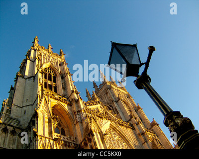 Die South façade of York Minster schoss vom Minster Yard aus und blickte nach oben in Richtung eines klaren blauen Himmels, mit einer traditionellen georgischen Straßenlampe im Vordergrund. Stockfoto