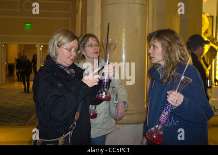 Drei Frauen mit Daiquiri Vasen genießen Nachtleben in Las Vegas vor dem Monte Carlo Hotel Stockfoto