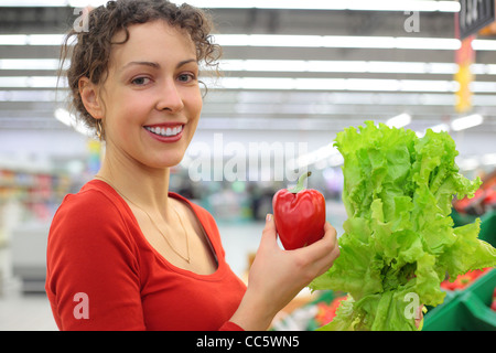 junge Frau im Shop mit roter Paprika und Salat Stockfoto