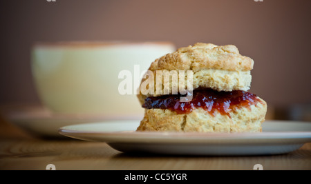 Traditionelle Scone mit Butter und Marmelade und Tee oder Kaffee im Hintergrund Stockfoto