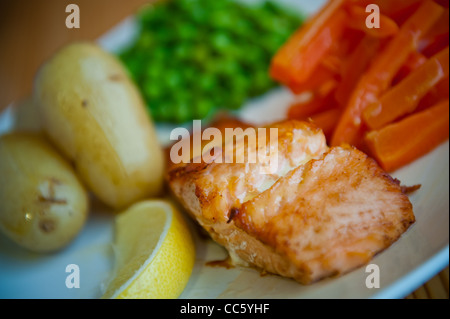 Schottischer Lachs mit Zitrone, Salzkartoffeln, Erbsen und Karotten Stockfoto