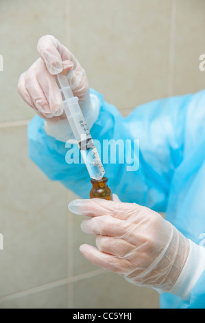 Laborantin mit Handschuhen und Schutzkleidung Stockfoto