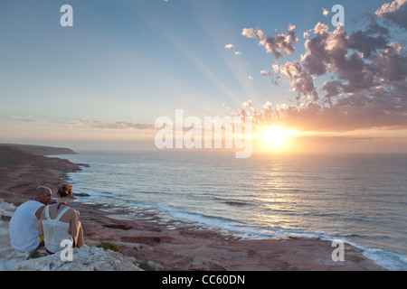 Ein paar genießen Sie einen atemberaubenden Sonnenuntergang von den Klippen von Red Bluff Beach in Kalbarri, Western Australia. Stockfoto