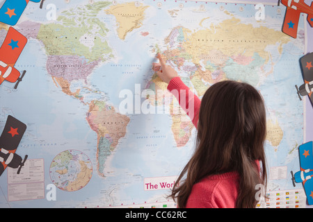 Junges Mädchen zeigt in verschiedene Länder auf der Weltkarte Stockfoto