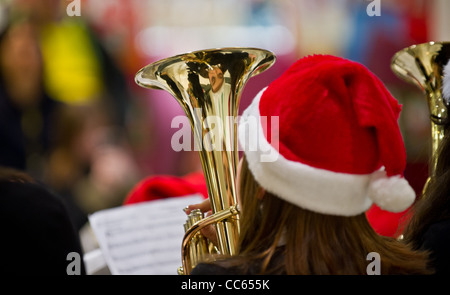 Ein junger Musiker, mit Santa Hut spielt ein Musikinstrument Messing Stockfoto