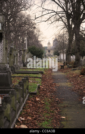 Ein Pfad auf einem Friedhof führt zu einer Kirche, umgeben von Grabsteinen. Stockfoto