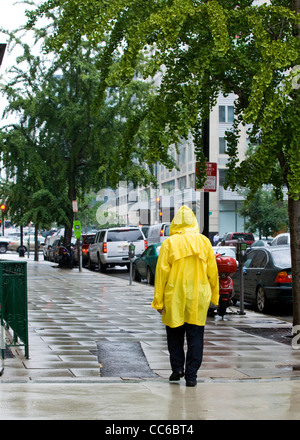 Ein Mann, der im Regen läuft und einen gelben Regenmantel trägt - USA Stockfoto