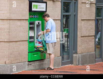 Ein Mann mit einem Outdoor-Geldautomaten mit Einkaufstasche - USA Stockfoto