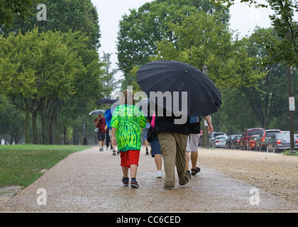 Eine Familie, die im Regen mit einem großen Regenschirm läuft - USA Stockfoto
