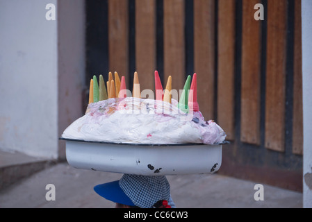 Ein Eisverkäufer Straße trägt seine Eis auf seinem Kopf mit bunten Zapfen an der Spitze in Saquisili, Ecuador herausragen. Stockfoto