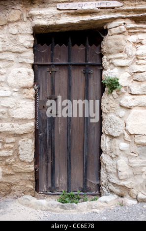 Eine alte braune vergitterte Tür in einem Stein Wand in Saignon, Frankreich Stockfoto