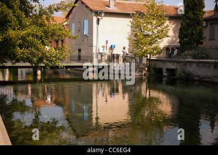 Verschiedene Häuser und Spazierwege sitzen an einem Kanal in einem kleinen Dorf in Frankreich Stockfoto