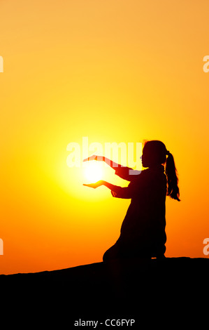 Indische Mädchen halten die Sonne. Silhouette. Indien