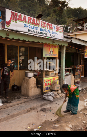 Indien, Arunachal Pradesh, Bhalukpong, Basar, Frau fegt staubigen Straße vor kleinen lokalen café Stockfoto