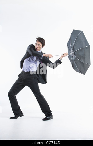 Ein Mann schlug durch den starken Wind mit einem Regenschirm in-und auswendig Stockfoto